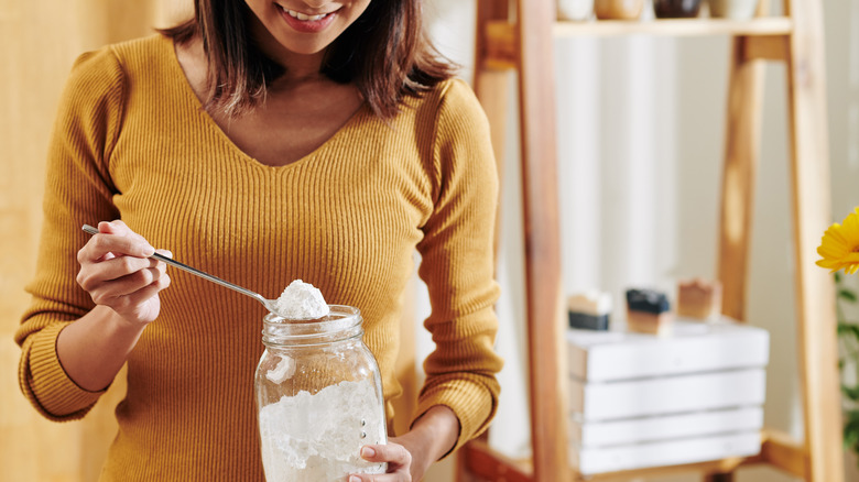 A woman taking baking soda out of a jar