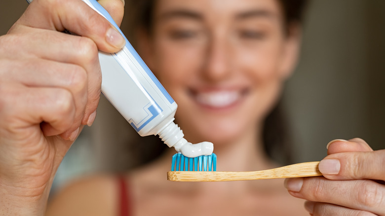 A woman applying toothpaste to her toothbrush