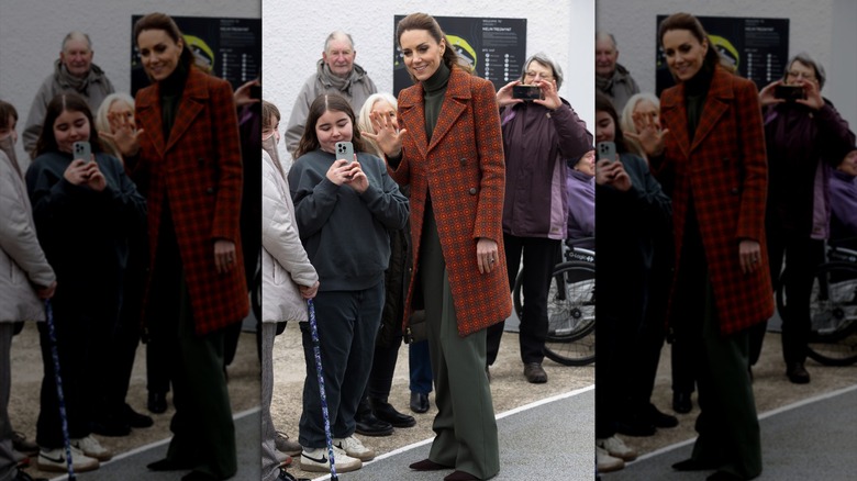 Kate Middleton waving to fans in Wales while wearing an orange coat