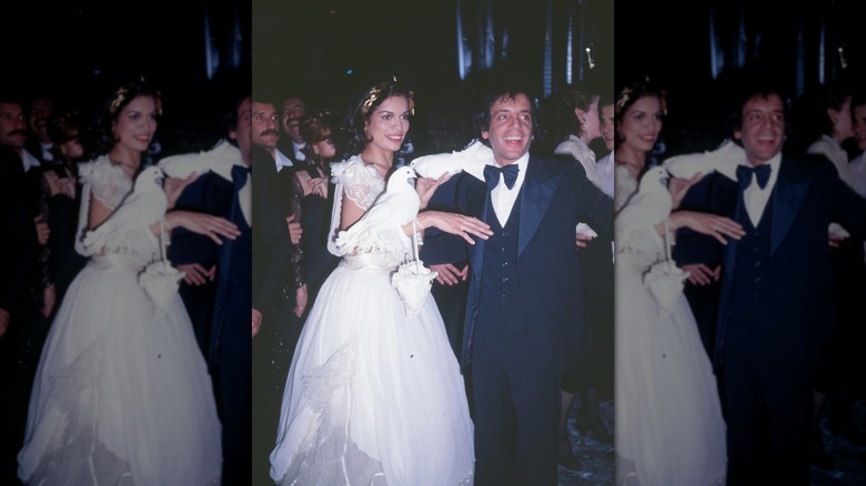 Bianca Jagger wearing a white ballgown adorned with doves standing with Steve Rubell at Studio 54.
