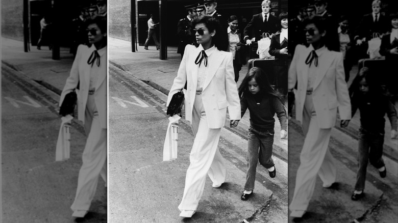 Bianca Jagger wearing a double-breasted white suit holding hands with daughter Jade.