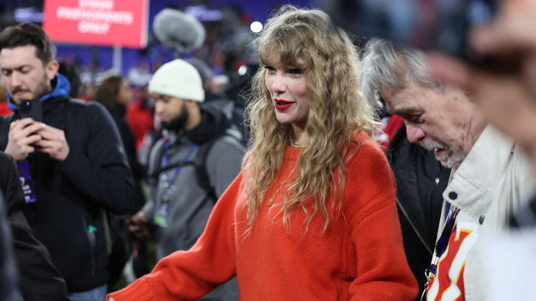 Taylor Swift with curly hair and an orange sweater