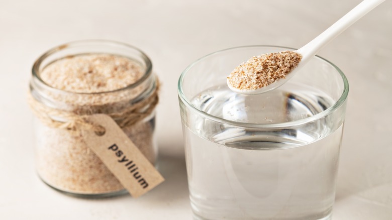 A scoop of psyllium husk pictured with a glass of water