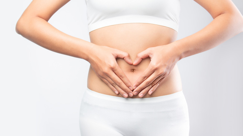 Woman creating a heart shape over her stomach with her hands