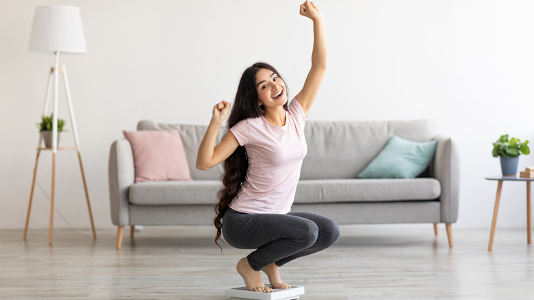 Woman celebrating the results on a scale