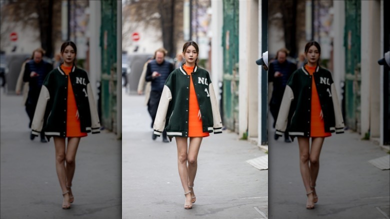 Woman wearing green sport jacket over orange dress
