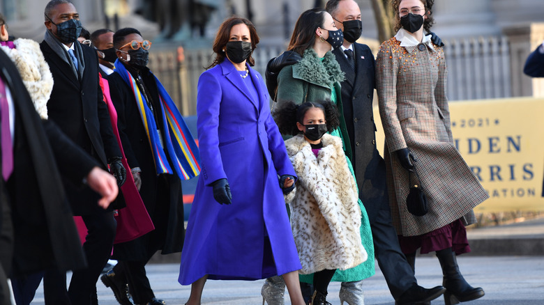 Kamala Harris walking in a blue-purple coat and dress at the 2021inauguration