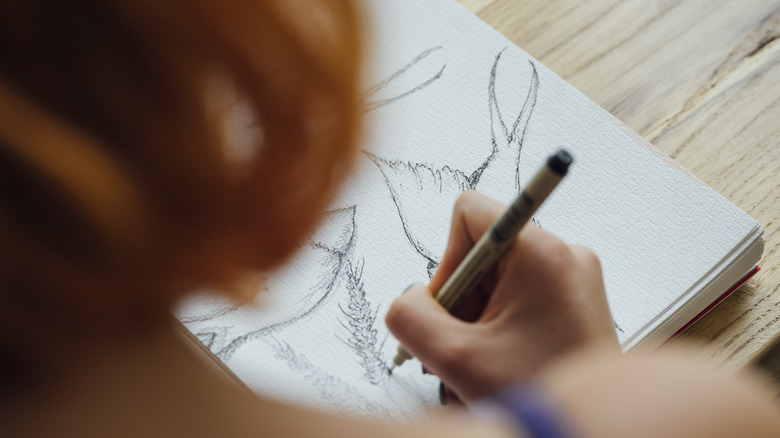 woman drawing in notebook