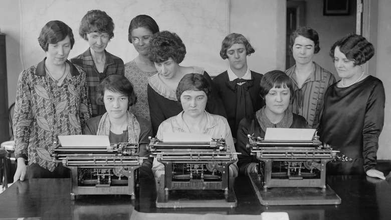 Several women standing around typewriters, 1926
