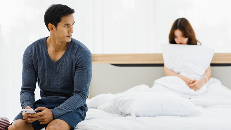 couple on bed looking awkward