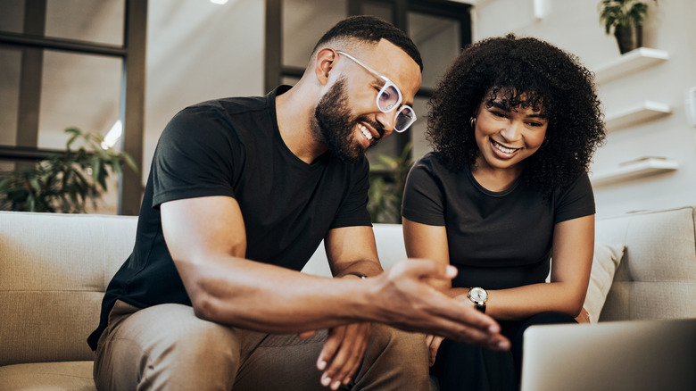 Couple smiling as they look at computer