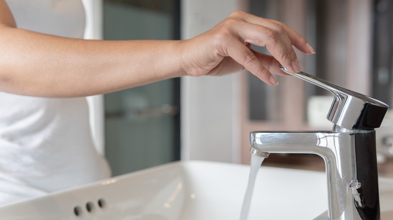 Woman turning sink water on