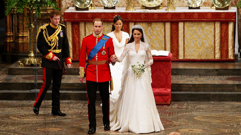 Kate Middleton in her wedding dress holding hands with Prince William as they prepare to leave