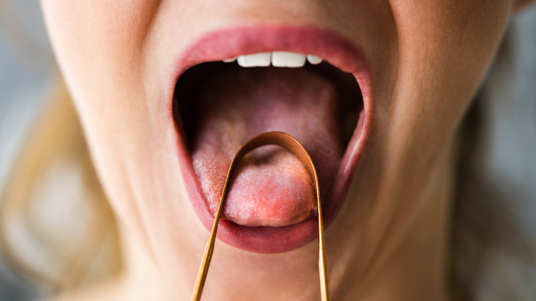 A woman scraping her tongue clean