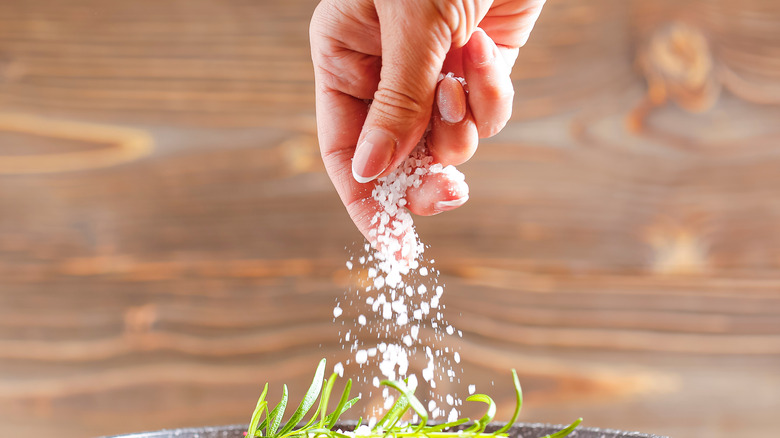 Woman adding salt to food
