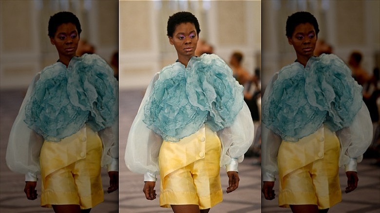 model walks runway wearing yellow and blue outfit