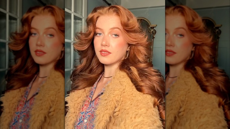 A woman posing with voluminous red hair.