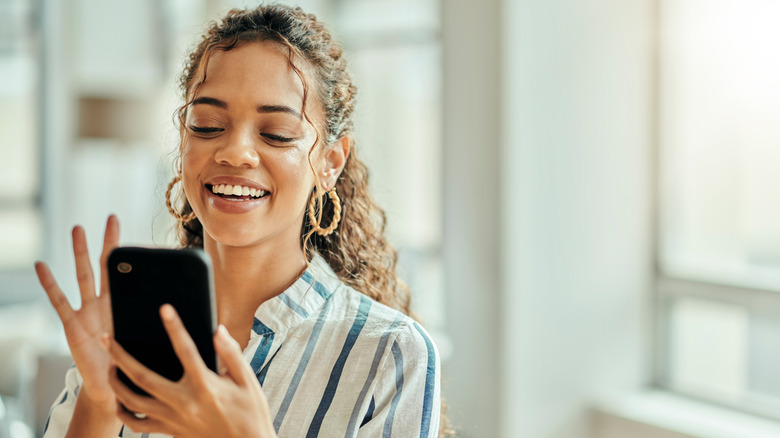A woman smiling at her phone.
