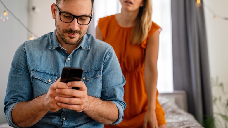 A woman peeking at her partner's phone.