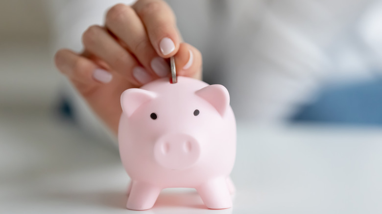 hand putting coin inside piggy bank