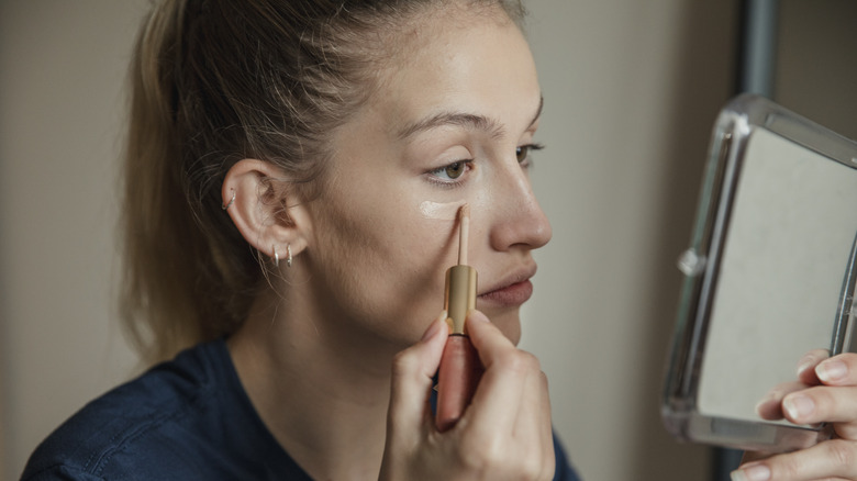 A woman applying concealer