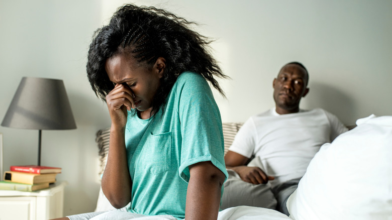 woman sad in bed man thinking 