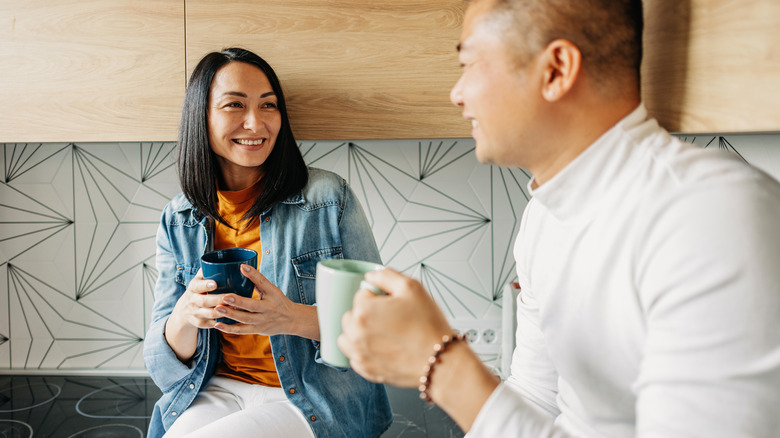 Asian couple talk in kitchen