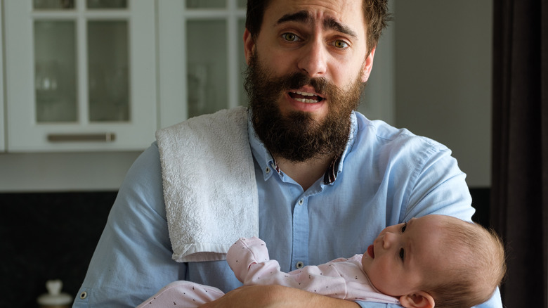 Flustered dad holding newborn