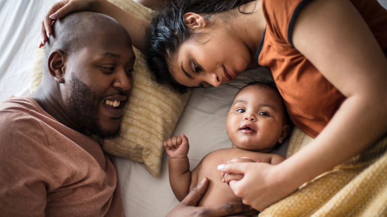 Family snuggling newborn in bed