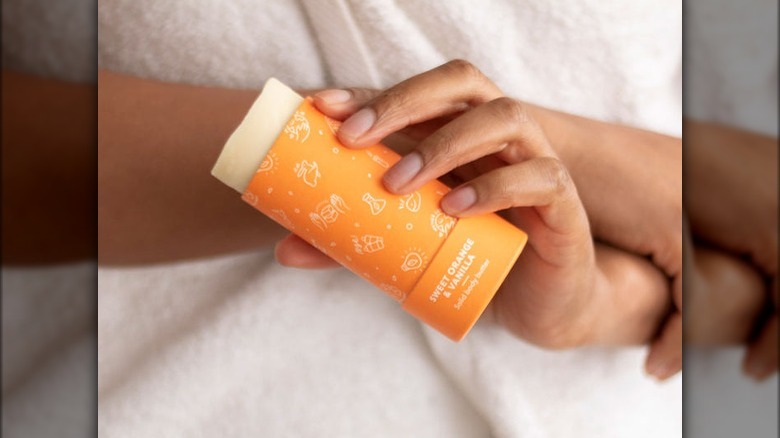 person using orange lotion stick