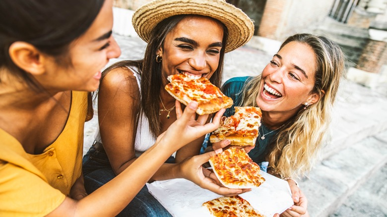 Three woman eating pizza