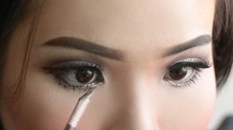 woman doing eye makeup