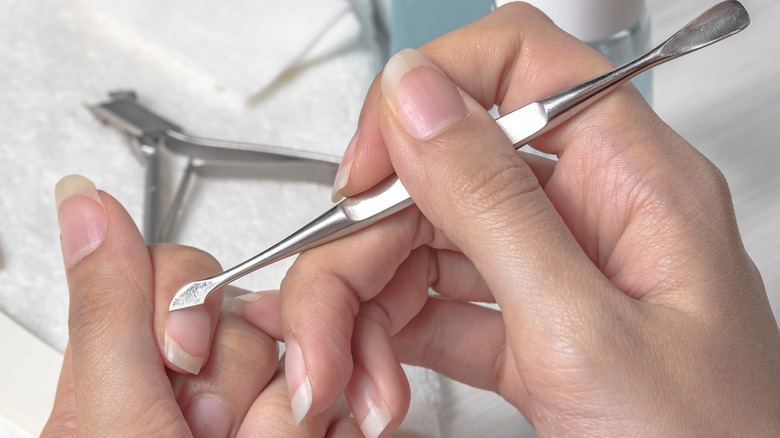 Woman pushing back her cuticles
