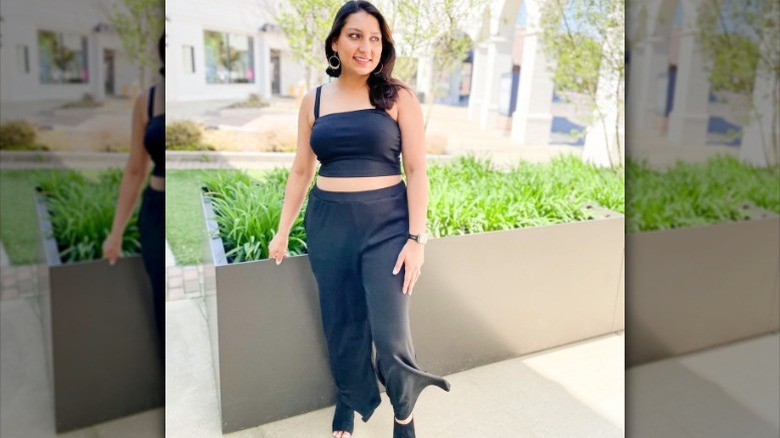 Woman wearing black crop top, pants