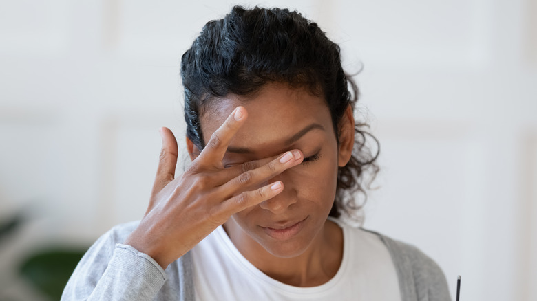 woman holding hand to eyes