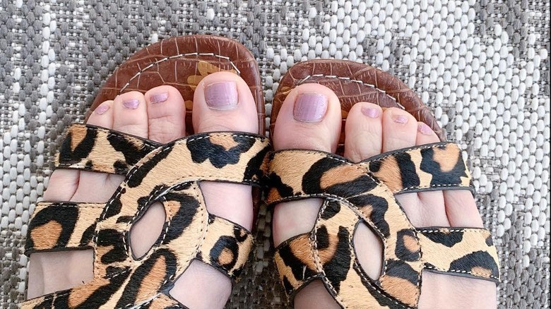 Person with mauve pedicure and orange shoes