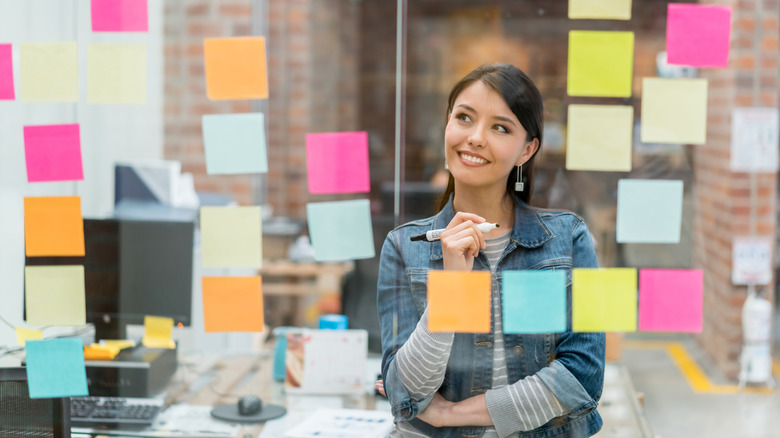 A woman looking at post-its on a dry erase board