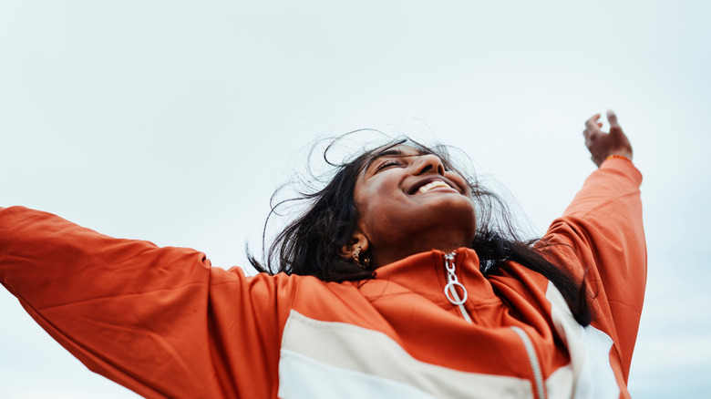 A woman smiling and throwing her hands up in victory