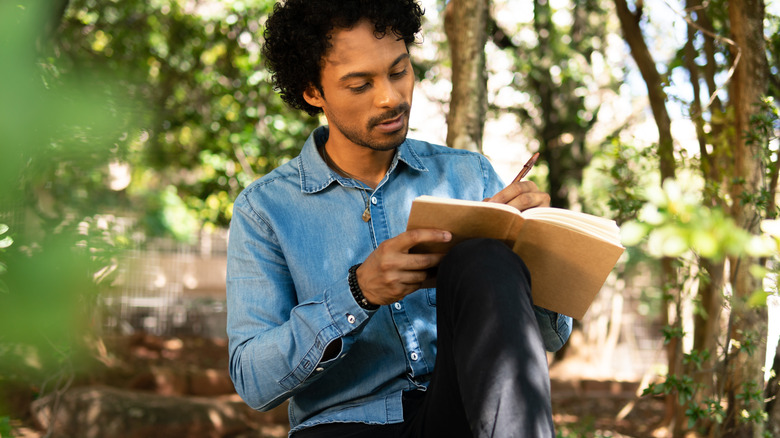 Man sitting in woods journaling