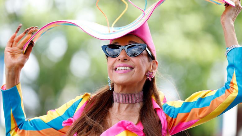 A woman wearing large sunglasses and a colorful and vibrant outfit