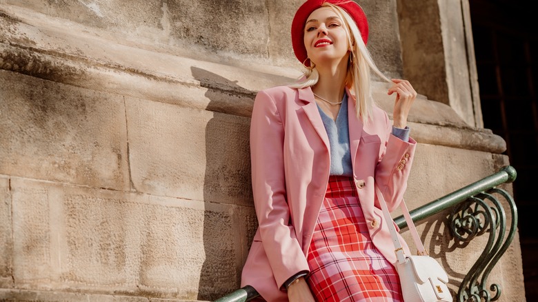 A girl sits on a staircase while wearing a red and pink skirt suit
