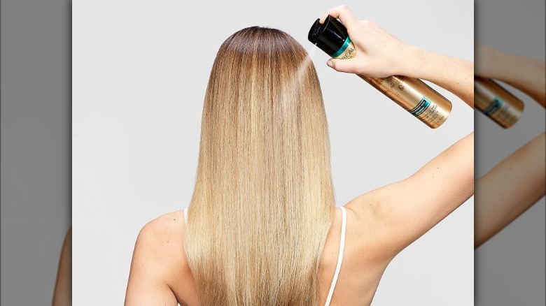 Blond person using Loreal hairspray