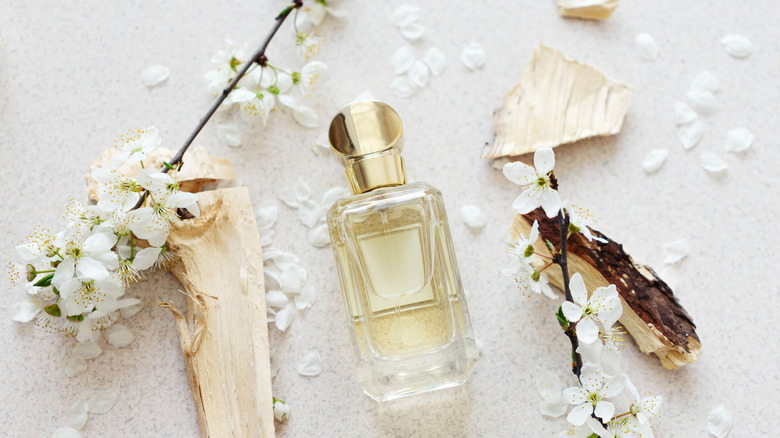 Fragrance bottle surrounded by petals and palo santo