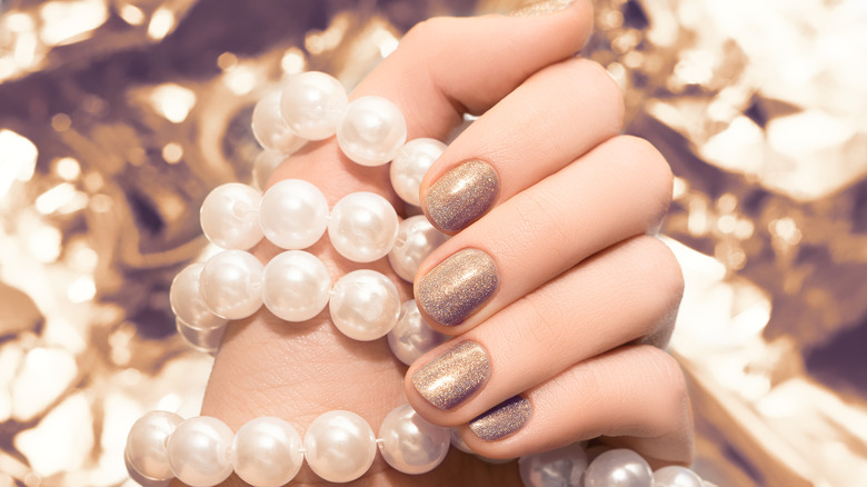 hand with glitter gold nail polish