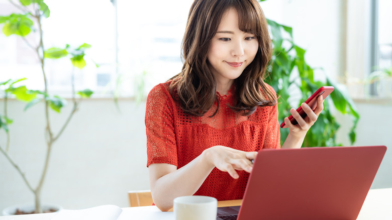 woman on her phone and computer at her desk