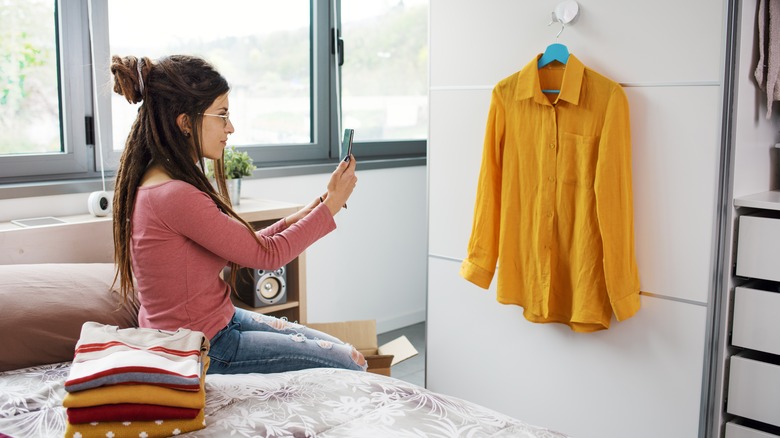 woman taking picture clothes on bed