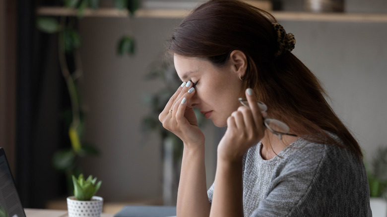 a woman with headache massages the bridge of her nose