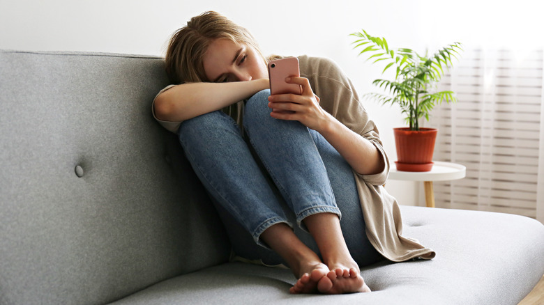 Woman looking at phone sad
