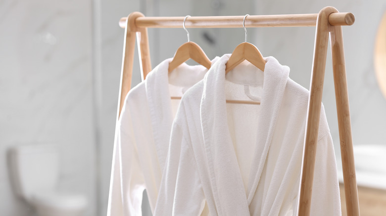 white bathrobe hanging on wood rack
