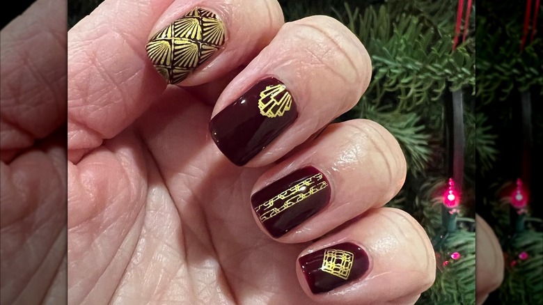 An art-deco manicure with burgundy-and-gold nails